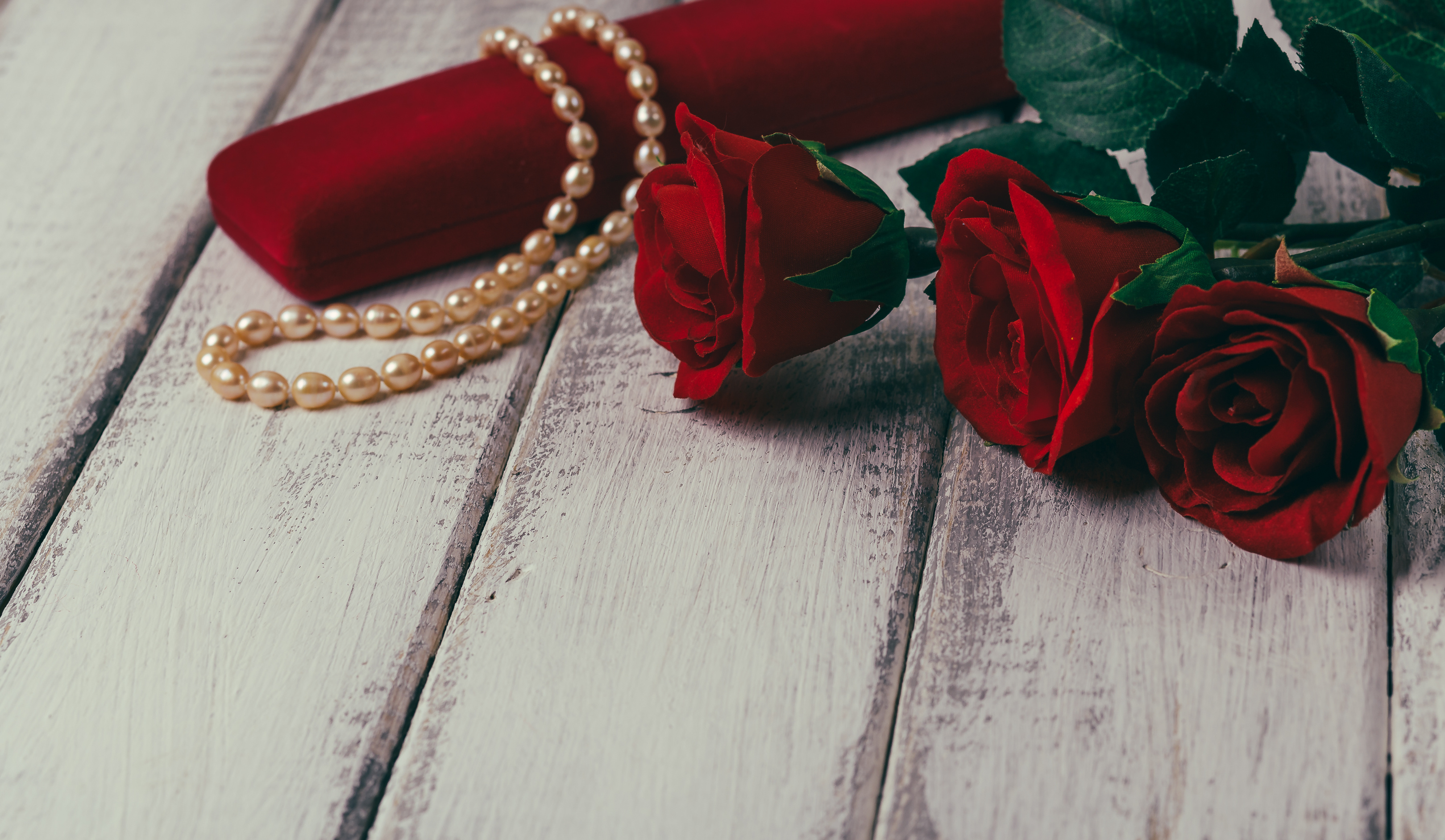 Roses and gift box with bead on wooden table. Valentines day concept. Copy space